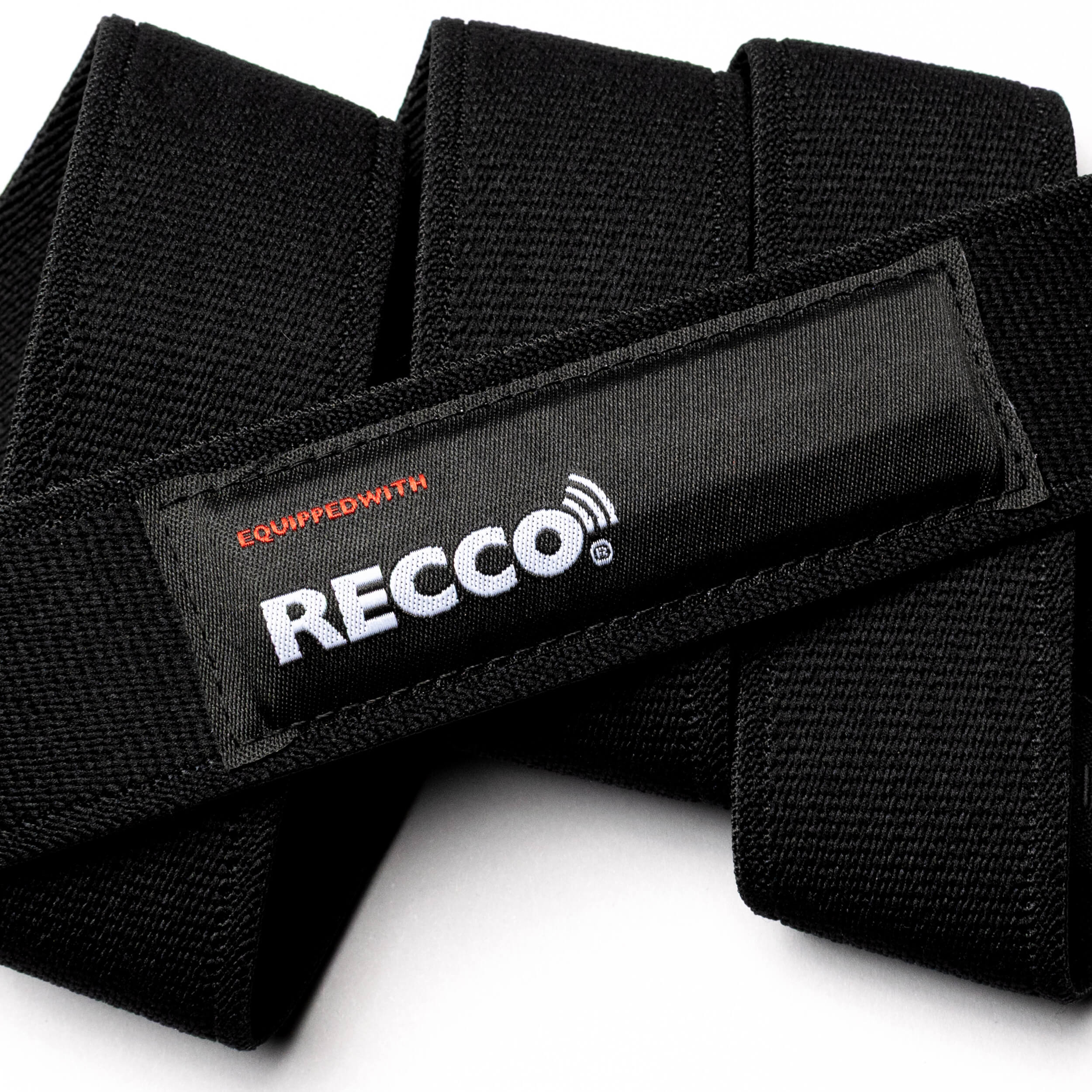 Close-up of the Arcade Belts Recco black performance stretch belt with a white and red "Equipped with RECCO" label, highlighting its textured fabric, detailed stitching, and integrated backup RECCO safety technology.