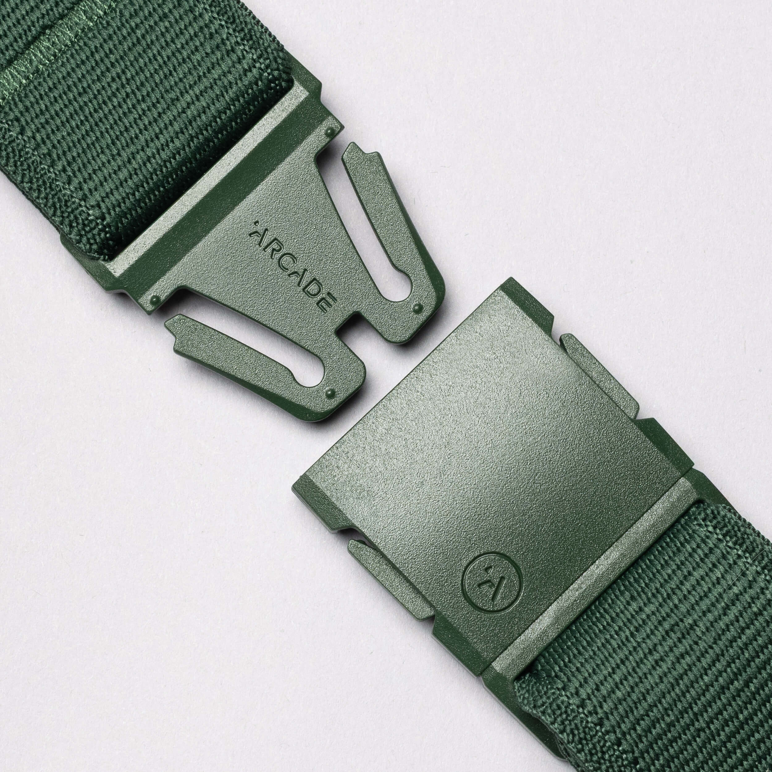 Close-up of the Atlas belt by Arcade Belts in green stretch webbing with a plastic buckle. The separated buckle ends display the ARCADE logo, set against a plain light grey background.