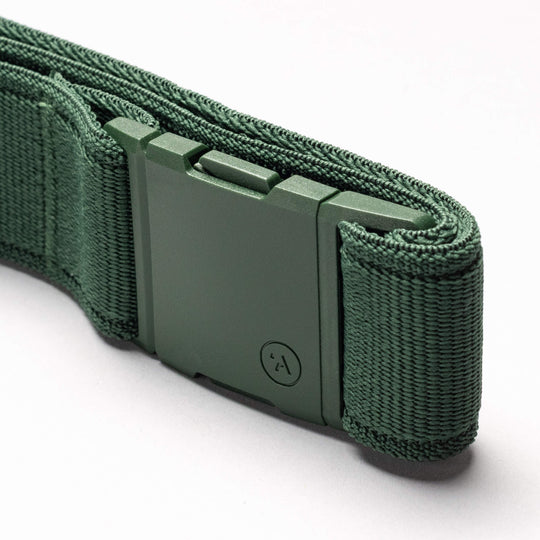 A close-up of the Atlas Elastic Stretch Belt by Arcade Belts in green, featuring a textured woven look and a low-profile rectangular buckle with a small circular symbol, displayed on a light background.