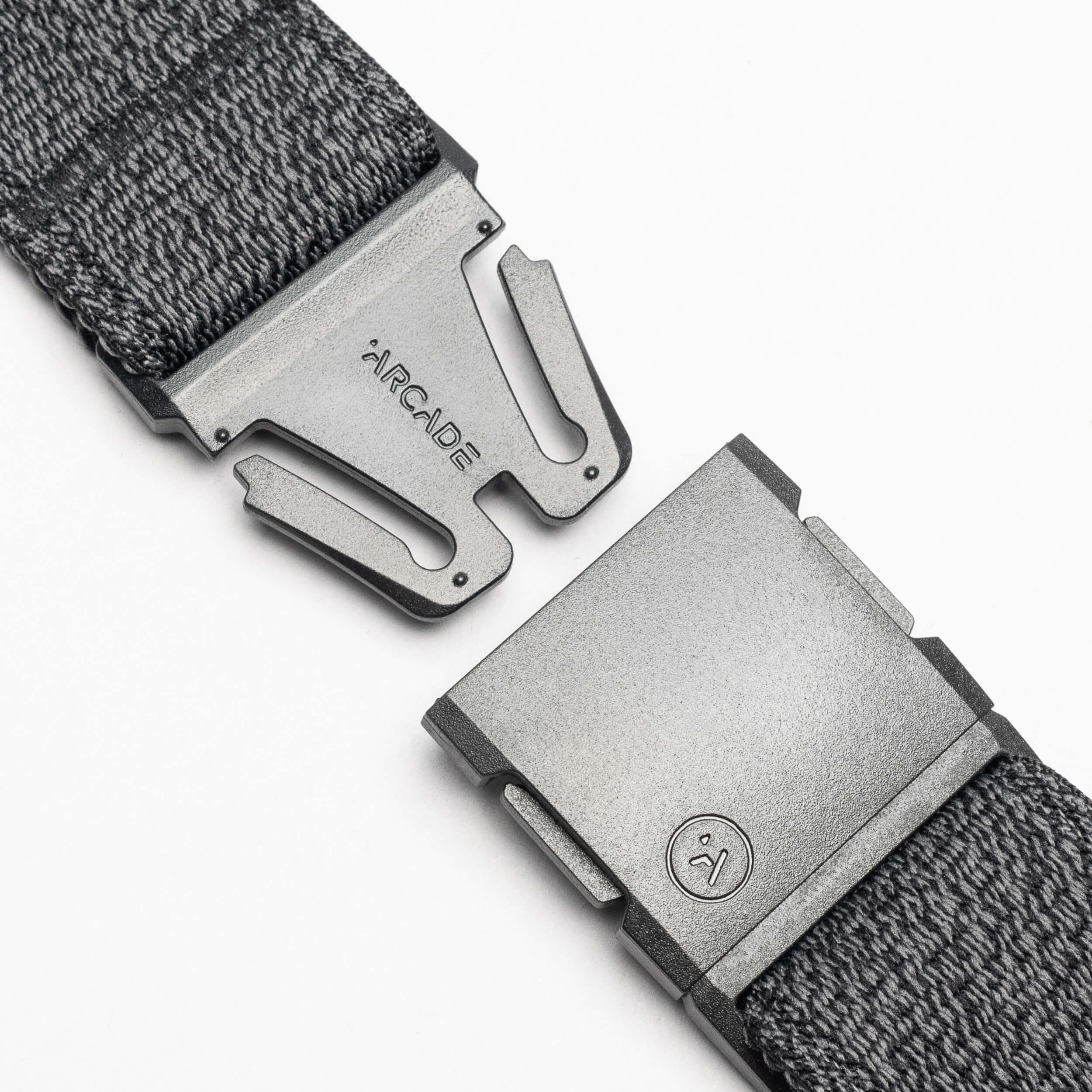 Close-up of the gray Atlas woven elastic stretch belt by Arcade Belts, featuring a metal clasp buckle. The partially open buckle shows ARCADE and a small logo on the metal against a white background.