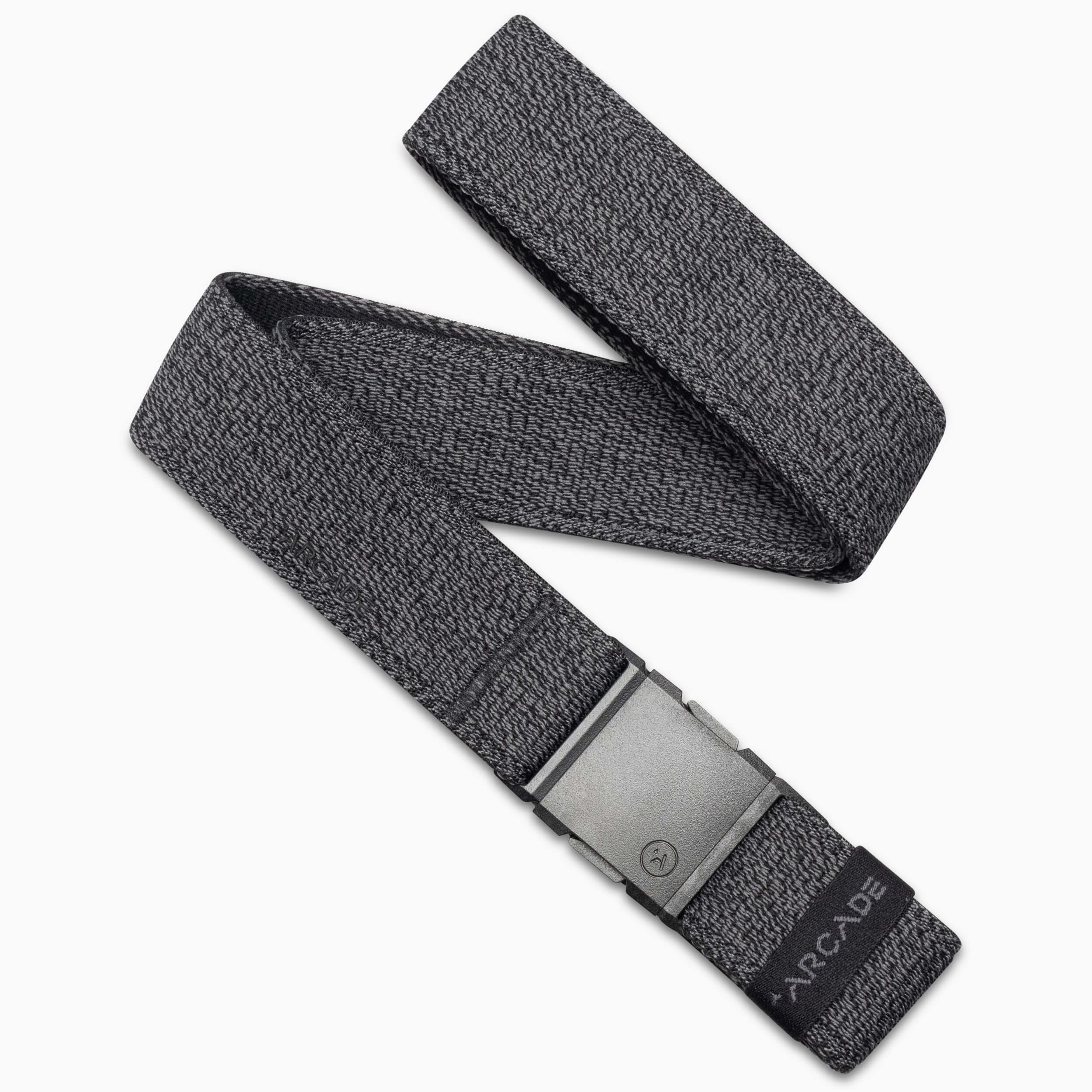 The Atlas by Arcade Belts is a grey woven elastic stretch belt with a matte gray rectangular plastic buckle, partially coiled. The end features a black tag printed with ARCADE.