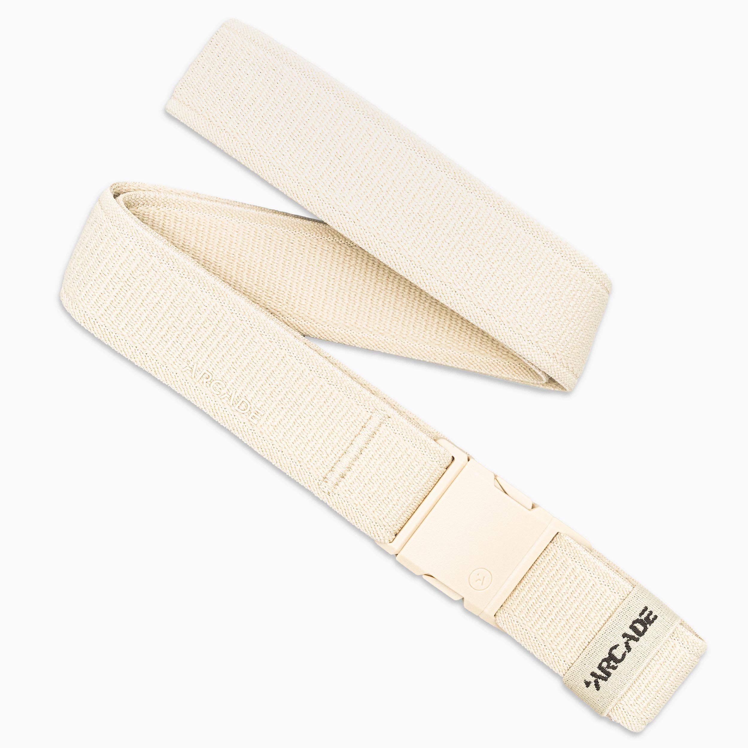 The Atlas by Arcade Belts is a beige stretch webbing belt with a matching low-profile plastic buckle, partially coiled and branded with ARCADE on one end—classic style and comfort.