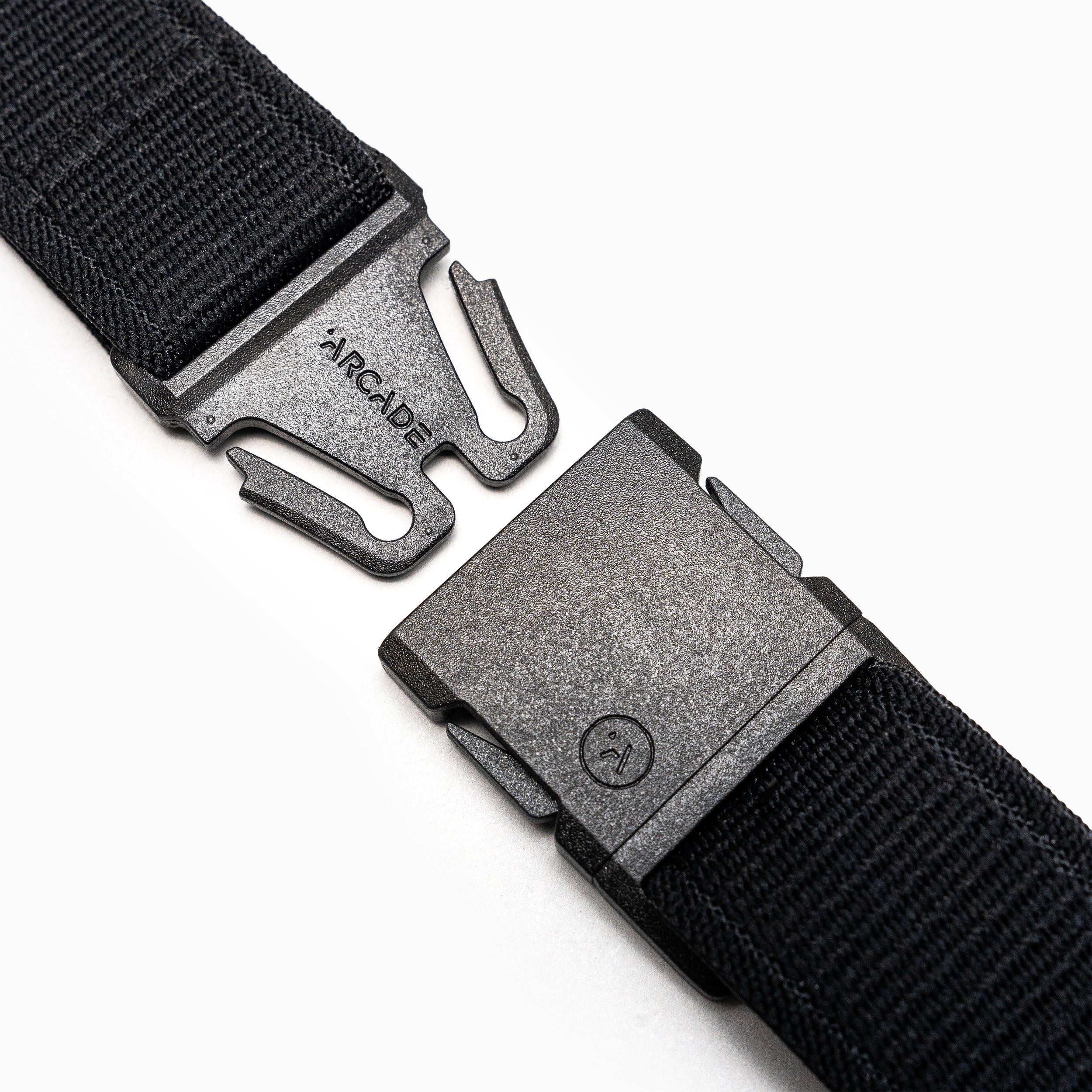 Close-up of the Atlas belt by Arcade Belts, a black elastic stretch belt with a metal quick-release buckle—partially unclasped, ARCADE engraved on one side. White background.