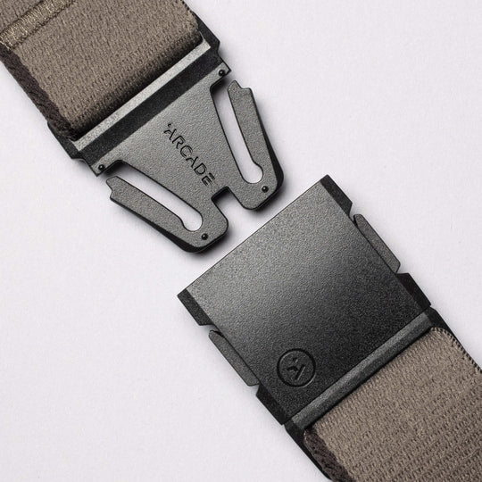 Close-up of a Blackwood A2 buckle in black metal with Arcade Belts branding on a taupe fabric strap, shown unfastened against a light background—ideal for adventurous explorers.