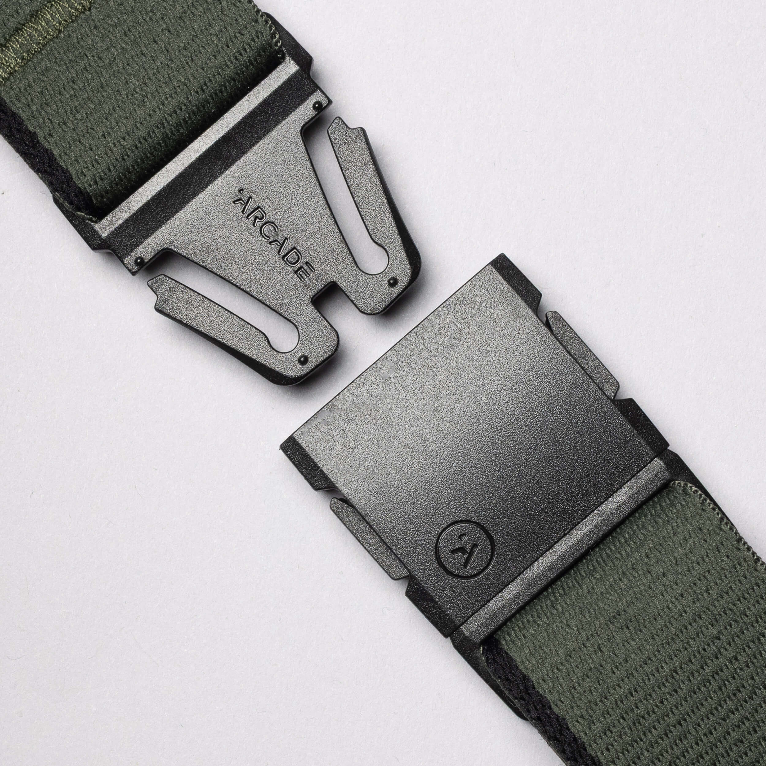 Close-up of Arcade Belts Blackwood: a green fabric belt with a partially unclasped black metal buckle, engraved with ARCADE and an A logo. Ideal for explorers. Plain white background.