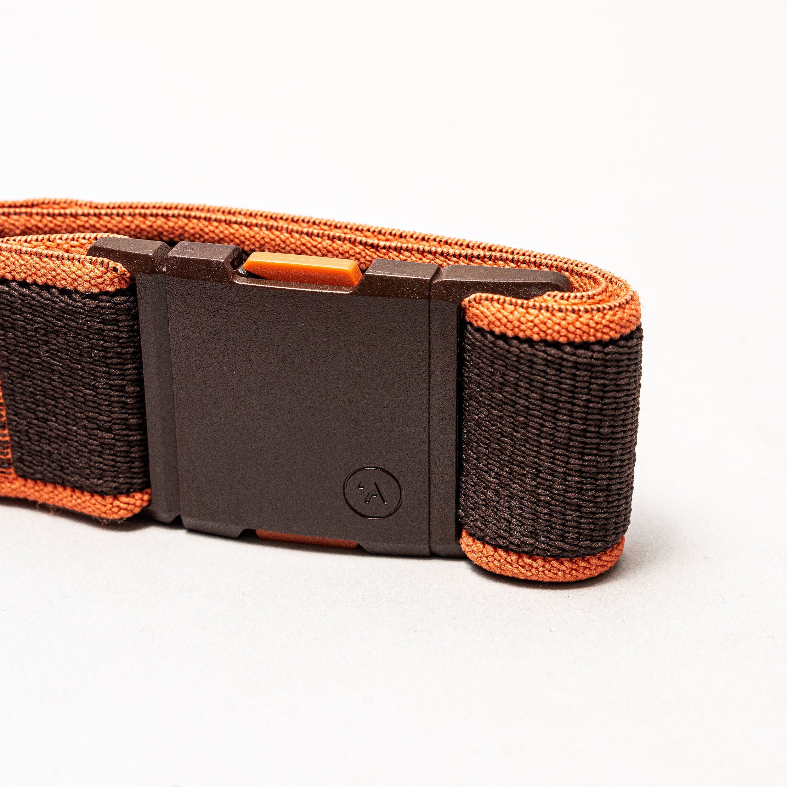 A close-up of the Arcade Belts Carto, a black and orange woven fabric low profile belt with a black rectangular plastic buckle, displayed on a plain white background.