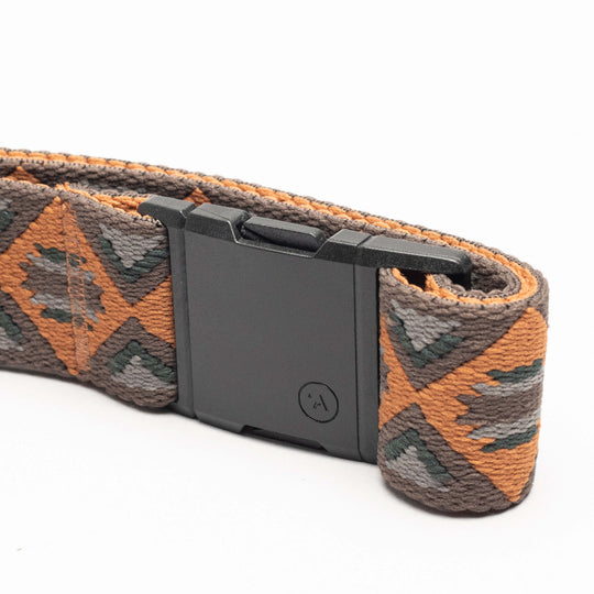 The Vernan Kee by Arcade Belts is a stylish elastic stretch belt with a geometric pattern in brown, orange, gray, and green, finished with a black rectangular plastic buckle. Ideal for travel or everyday comfort.