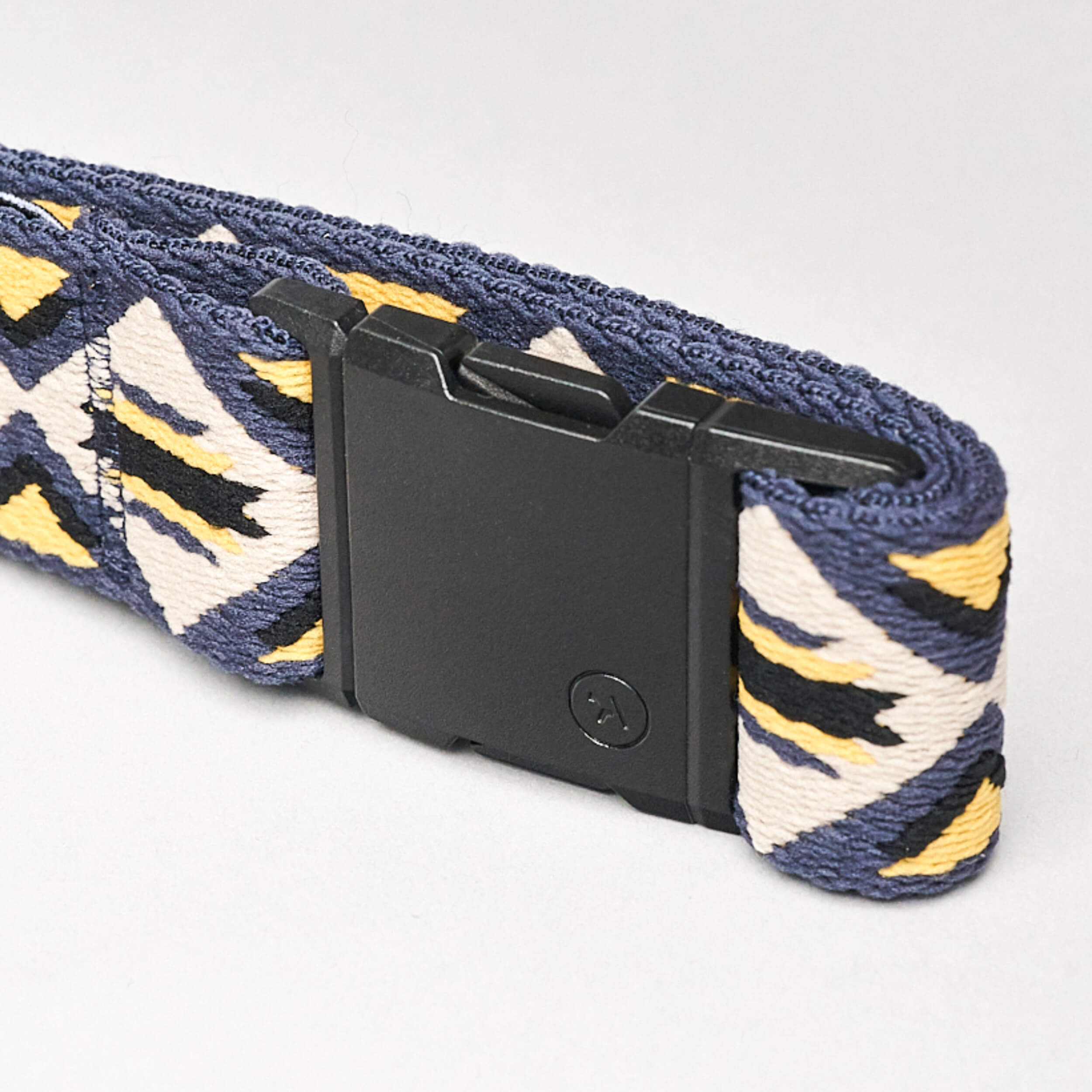 A close-up of the Vernan Kee belt by Arcade Belts, showcasing Navajo rug-inspired geometric patterns in blue, yellow, and white, finished with a black rectangular plastic buckle.