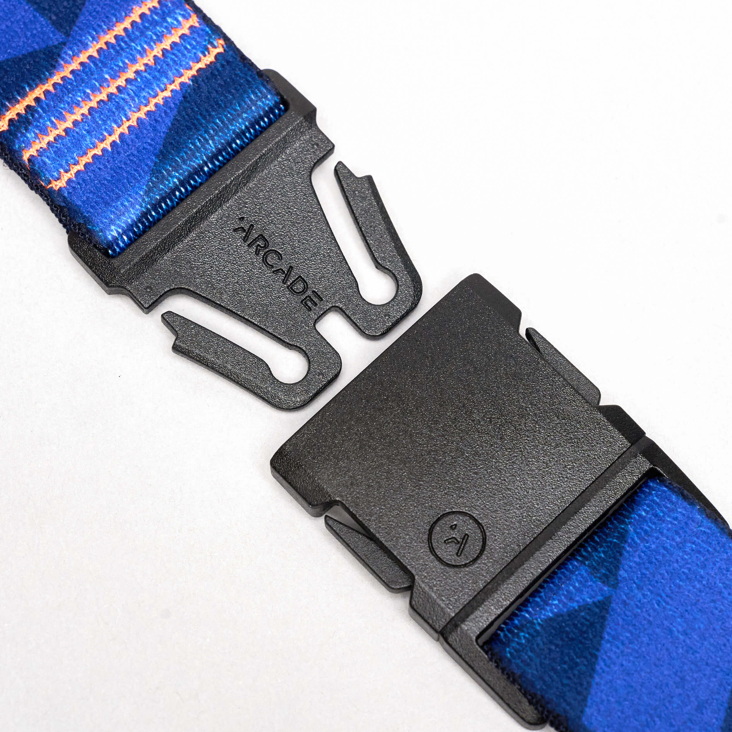 Close-up of an Arcade Belts DDC elastic stretch belt in blue pattern with an orange stripe, featuring a partially unlatched black plastic buckle displaying the ARCADE brand name.