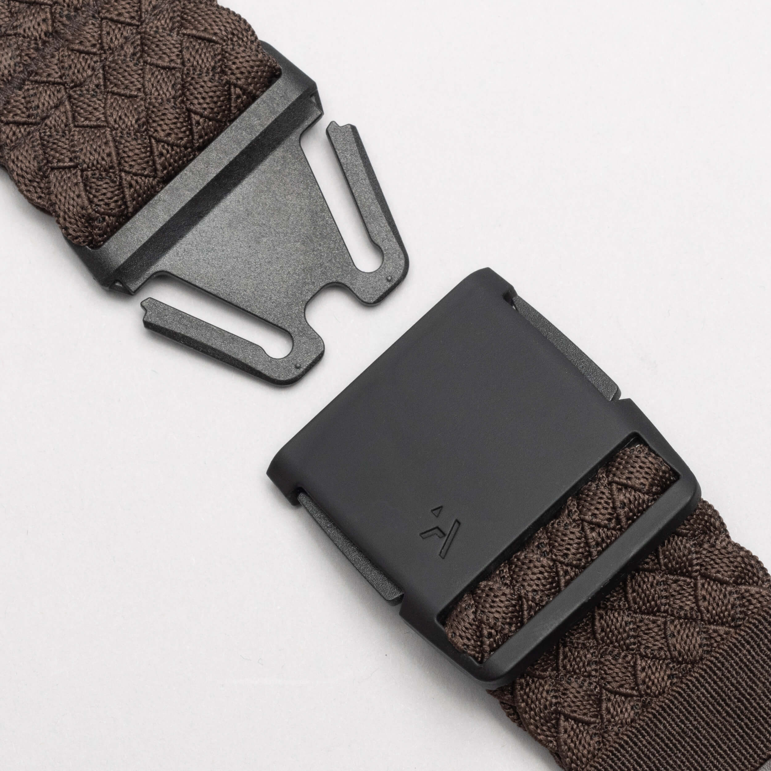 Close-up of the Arcade Belts Futureweave: a dark brown stretch webbing strap featuring a matte black low profile buckle and clasp, shown open on a light background to reveal its fastening mechanism.