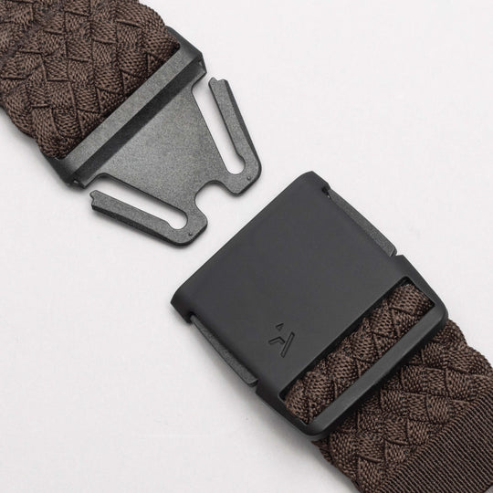 Close-up of the Arcade Belts Futureweave: a dark brown stretch webbing strap featuring a matte black low profile buckle and clasp, shown open on a light background to reveal its fastening mechanism.