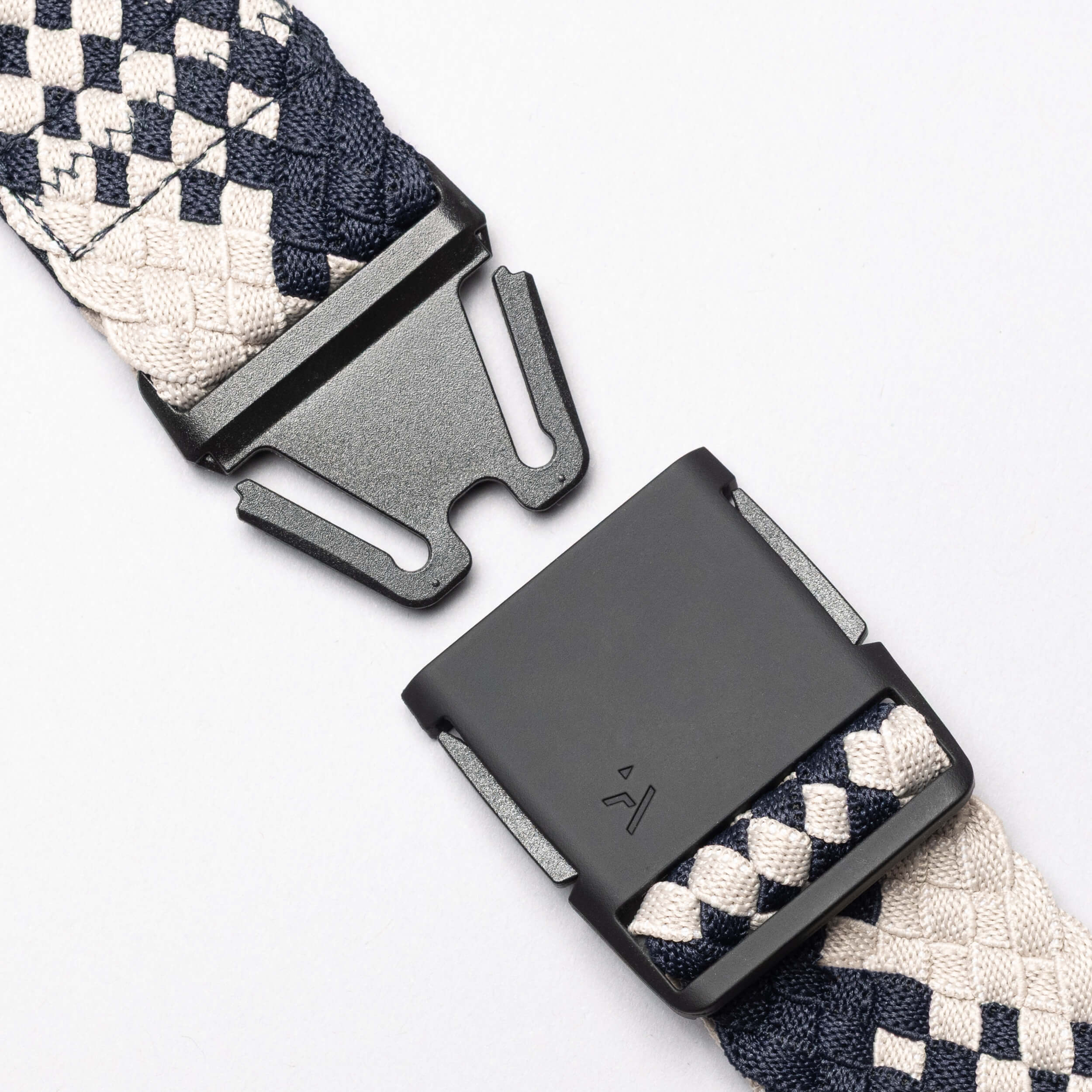 Close-up of the Arcade Belts Futureweave: a black metal buckle with navy blue and cream patterned woven webbing strap, shown unfastened on a white background—an ideal choice for a comfortable belt.