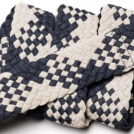 A close-up of Arcade Belts' Futureweave showcases intricately braided webbing in a black and white checkered pattern, giving it a stylish, textured look reminiscent of a comfortable belt.