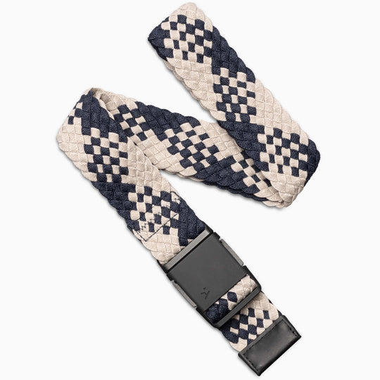 The Arcade Belts Futureweave is a lightweight belt made from woven webbing in a navy blue and beige checkered pattern, featuring a black rectangular metal buckle. Its partially coiled, flexible design ensures comfort and style.