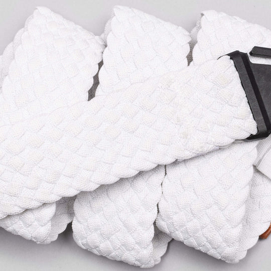 A close-up of Arcade Belts Futureweave: a textured white stretch webbing belt with a black metal buckle, coiled on a light surface—an ideal low profile travel belt.