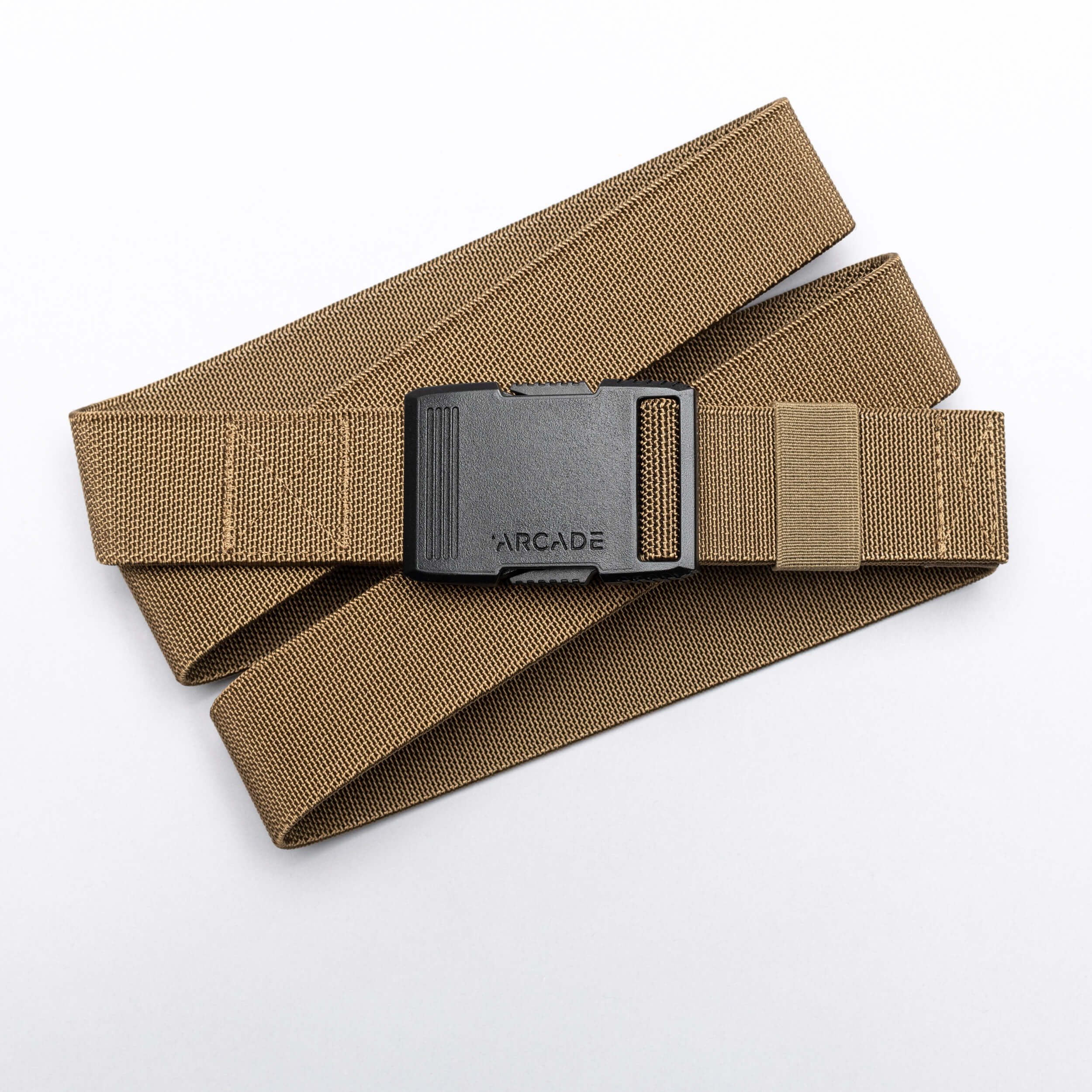 A tan Arcade Belts Hardware elastic stretch belt with a black plastic buckle, labeled ARCADE, is coiled neatly on a white background.