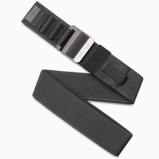 The Arcade Belts Hardware Alu is a black stretch webbing belt with a rectangular metal buckle engraved with ARCADE. Its textured pattern and low-profile design make it ideal as a sleek, travel-friendly accessory.