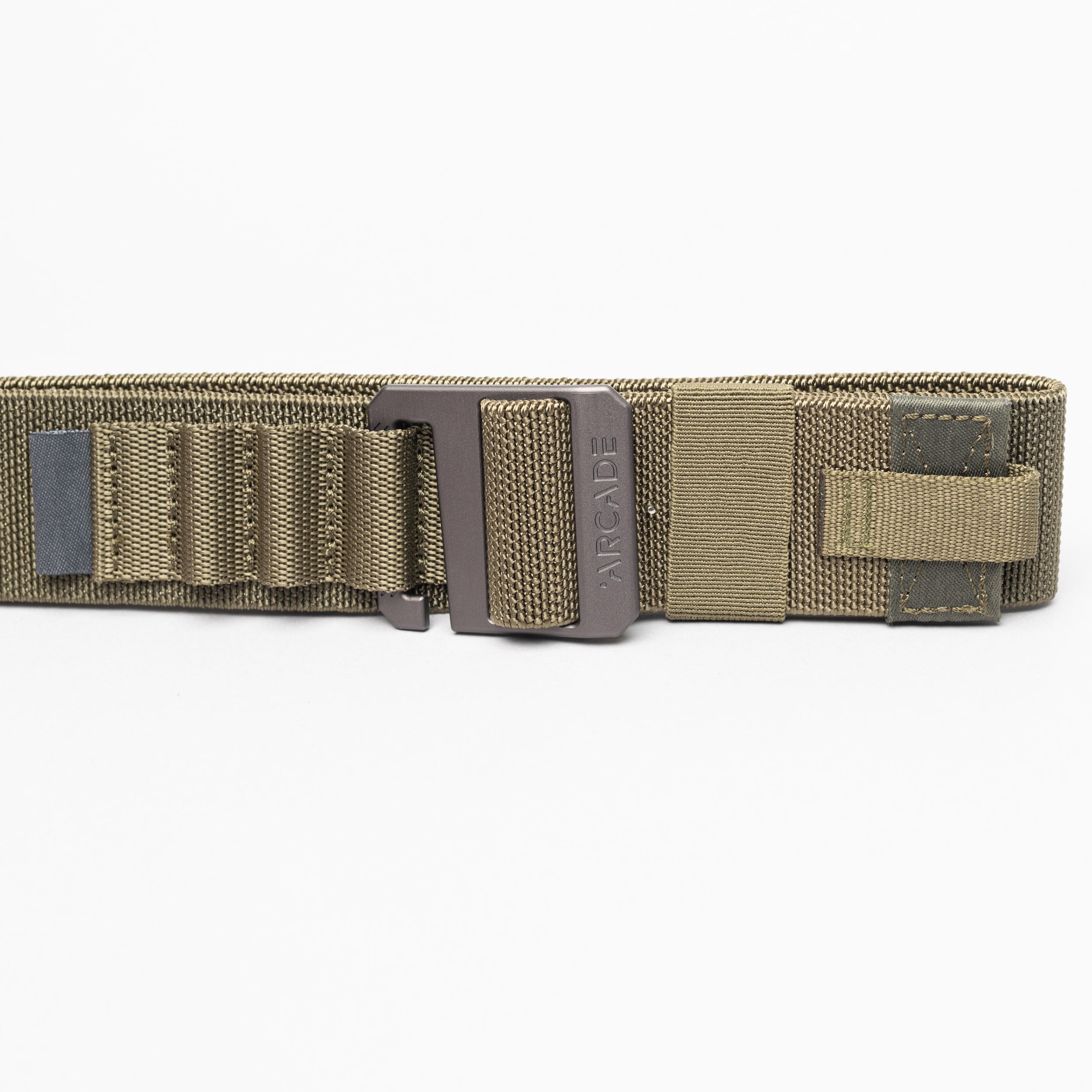 A close-up of the olive green Arcade Belts Hardware Alu tactical belt with a metal buckle, reinforced stitching, webbing loops, and Velcro strap. This low-profile belt offers durability and comfort against a white background.