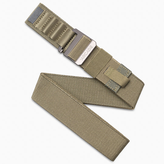 The Hardware Alu by Arcade Belts is a tan woven elastic stretch belt with a metal buckle, displayed partially unrolled on a white background.