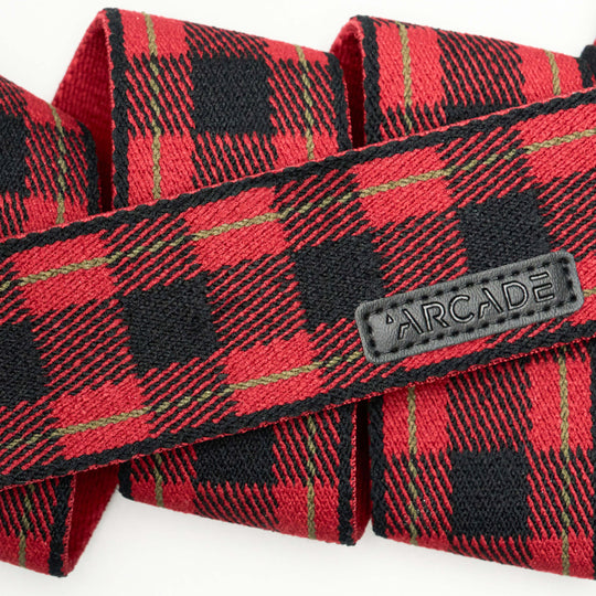 A close-up of Arcade Belts Plaid, a red and black stretch webbing belt, featuring a stitched black label reading ARCADE.