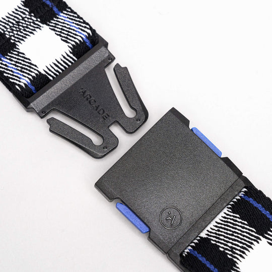 Close-up of the Arcade Belts Plaid: a low-profile black buckle with Arcade branding, attached to a black, white, and blue plaid woven strap. Shown unclasped against a white background—ideal for travel.