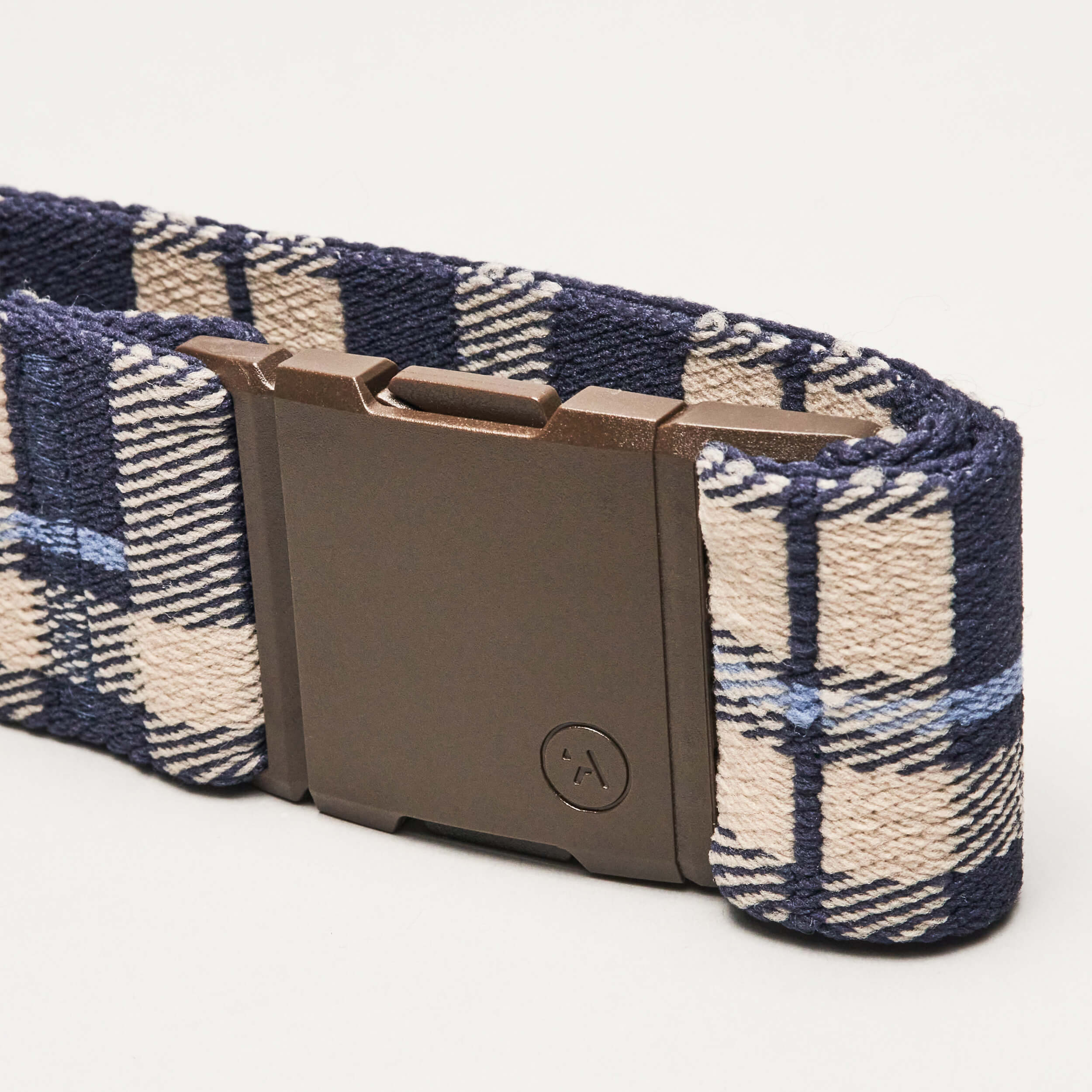 A close-up of the Arcade Belts Plaid Low Profile Belt in blue and beige plaid, featuring a rectangular dark plastic buckle, shown against a plain white background.