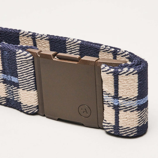 A close-up of the Arcade Belts Plaid Low Profile Belt in blue and beige plaid, featuring a rectangular dark plastic buckle, shown against a plain white background.