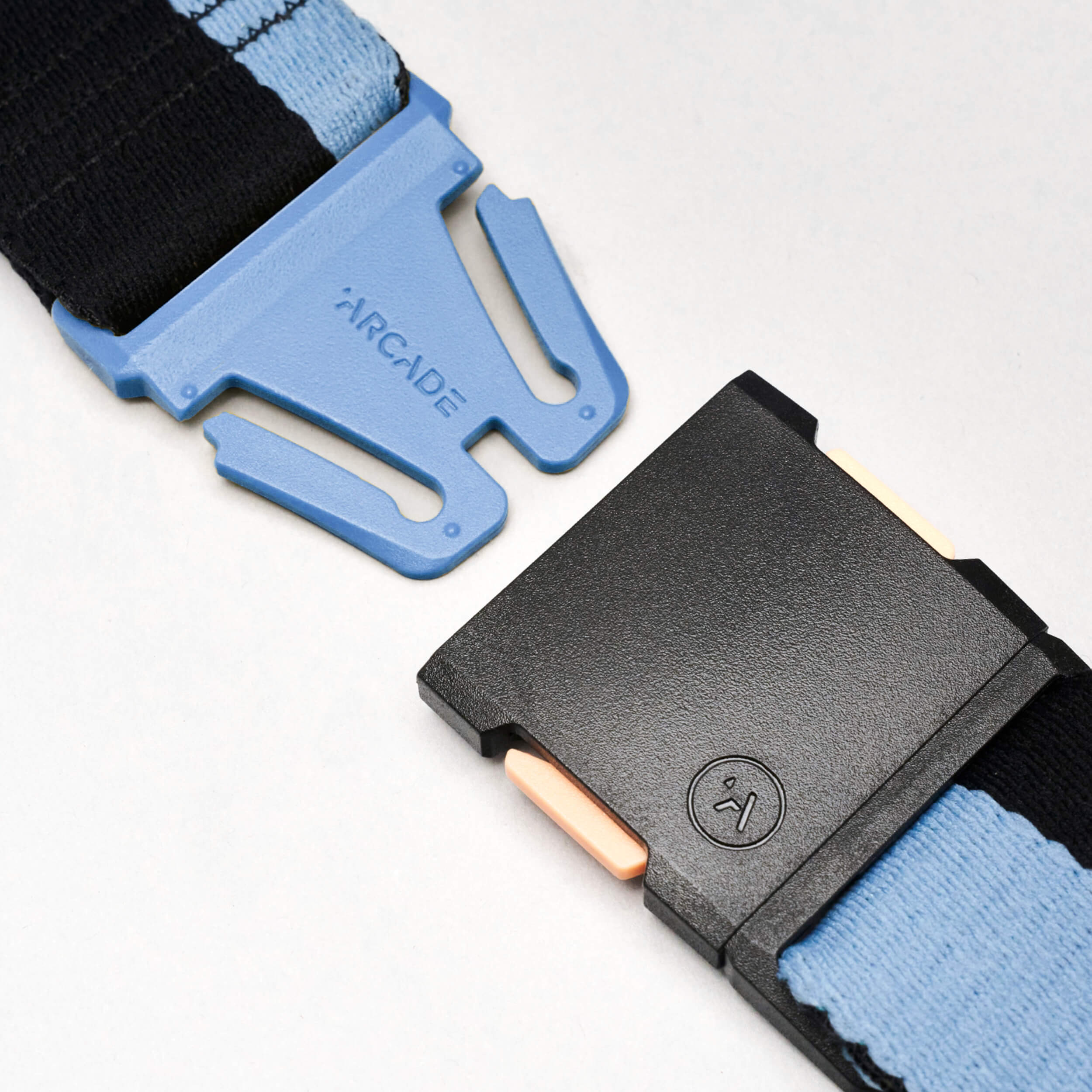 Close-up of the Sierra belt by Arcade Belts, featuring a blue and black adjustable strap with a plastic buckle. The blue section is labeled Arcade, while the black section has a textured button and beige release tabs.