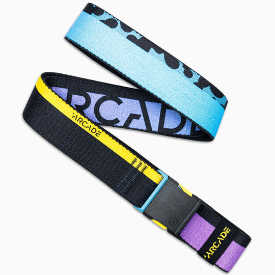 The Arcade Belts Sierra is a woven low-profile belt with stretch webbing, blue and black upper, bold “ARCADE” text, a black lower with yellow/purple accents, and a plastic buckle featuring the ARCADE logo in yellow.