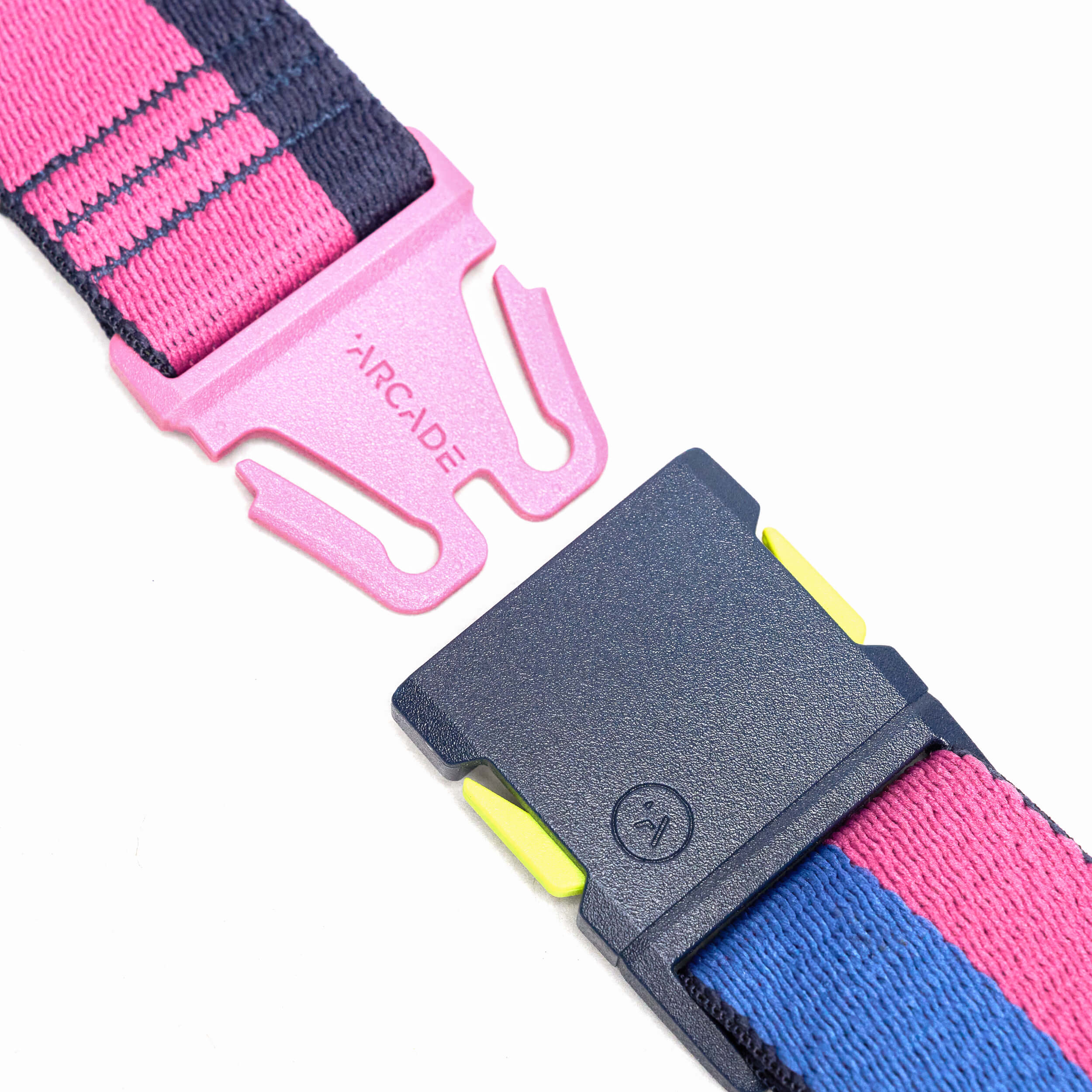 Close-up of a plastic buckle on the Sierra belt by Arcade Belts, featuring a pink and dark blue design with yellow accents. The elastic strap has pink and blue stripes, with ARCADE printed on the pink buckle—showcasing their unique style.