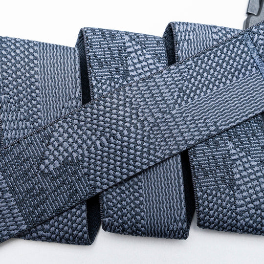 Close-up of several gray Skyline belts by Arcade Belts, featuring woven, textured webbing straps arranged in overlapping layers against a white background.