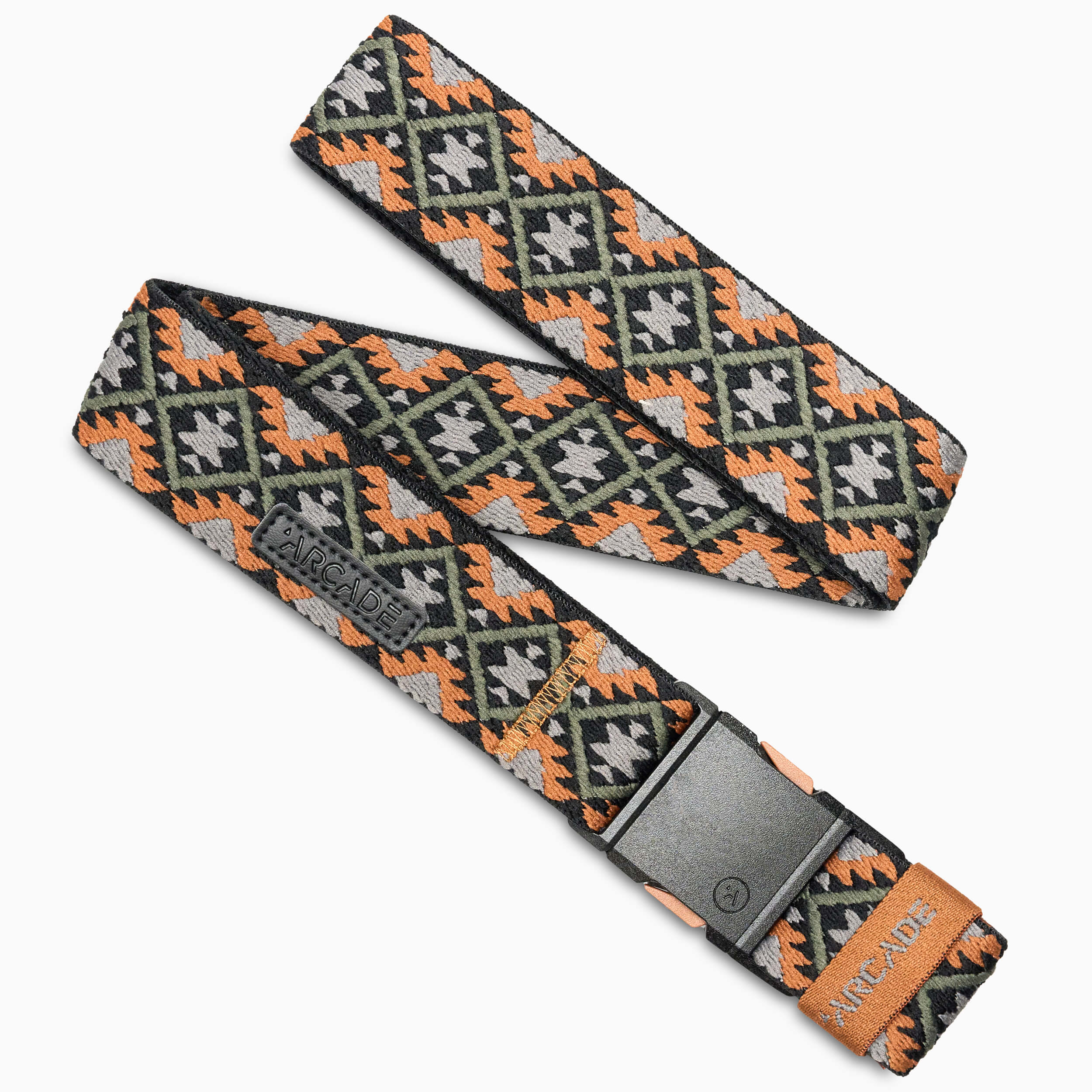 The Vernan Kee by Arcade Belts is a woven belt with a geometric diamond pattern in black, orange, gray, and beige. It features a rectangular plastic buckle and an orange Arcade tag near the buckle.